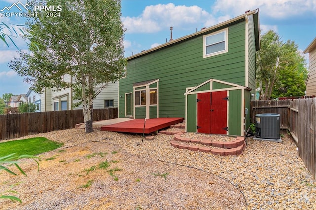 rear view of property featuring cooling unit, a wooden deck, and a storage unit