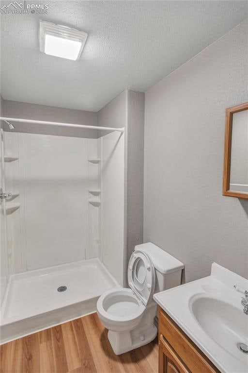 bathroom featuring vanity, toilet, walk in shower, and hardwood / wood-style floors