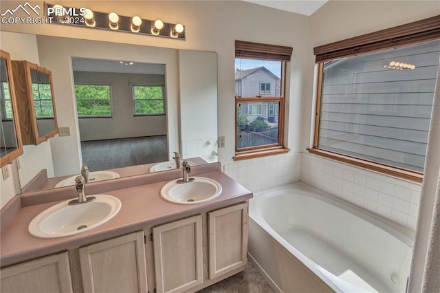 bathroom featuring a tub to relax in, vanity, and plenty of natural light