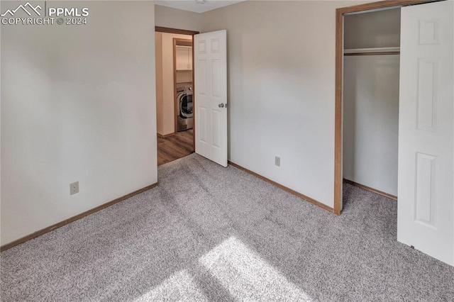 unfurnished bedroom with carpet flooring, washer / dryer, and a closet