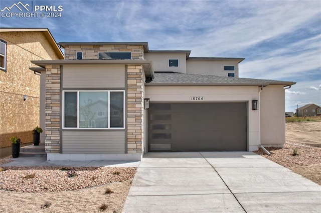 view of front of property with driveway, a garage, stone siding, and stucco siding