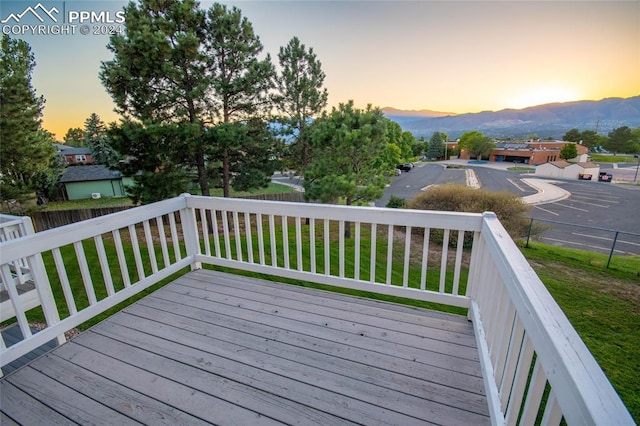 deck at dusk featuring a lawn and a mountain view