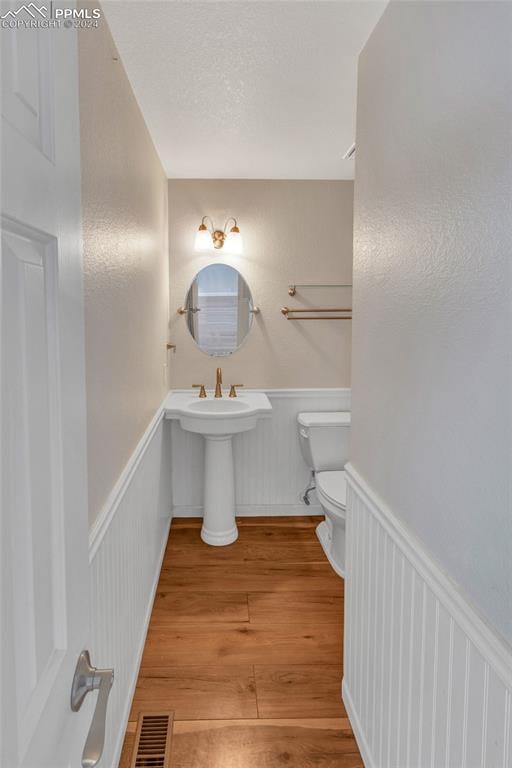 bathroom with toilet and hardwood / wood-style flooring