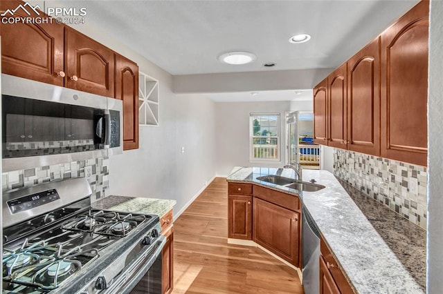 kitchen featuring light hardwood / wood-style flooring, stainless steel appliances, light stone countertops, and sink