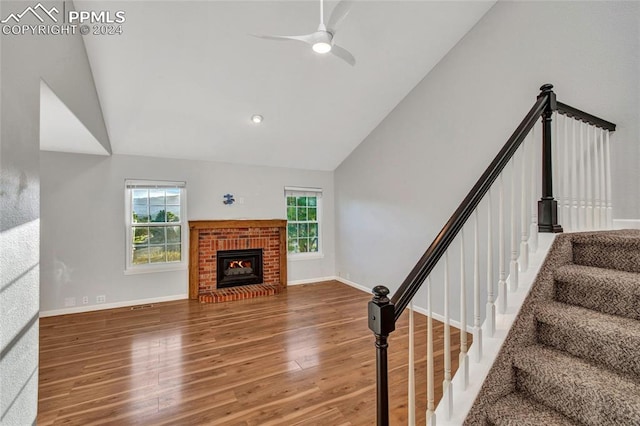 living room with wood-type flooring, a brick fireplace, high vaulted ceiling, and ceiling fan