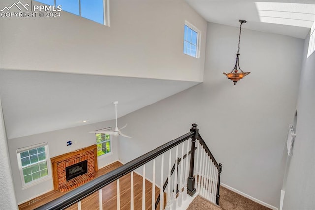 stairway featuring vaulted ceiling with skylight, ceiling fan, hardwood / wood-style flooring, and a fireplace