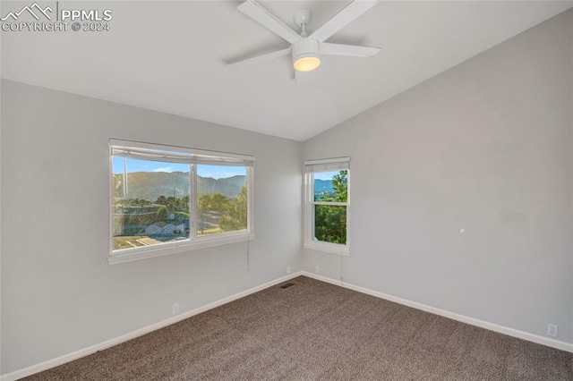 unfurnished room featuring lofted ceiling, ceiling fan, a mountain view, and carpet flooring