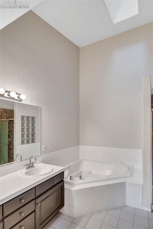 bathroom featuring a skylight, vanity, plus walk in shower, and tile patterned flooring