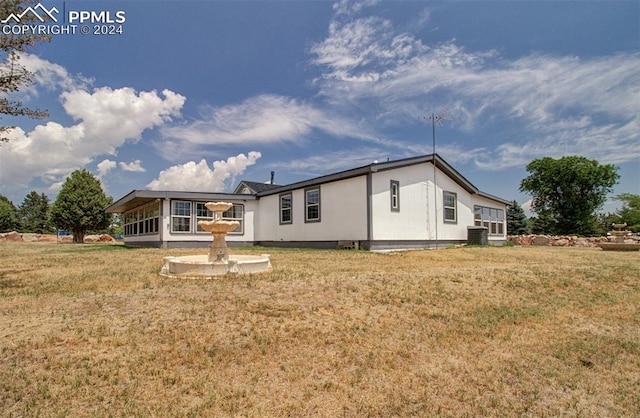 back of property with central AC and a lawn