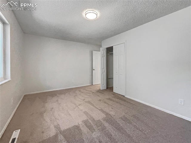 unfurnished bedroom featuring a textured ceiling, a closet, and carpet