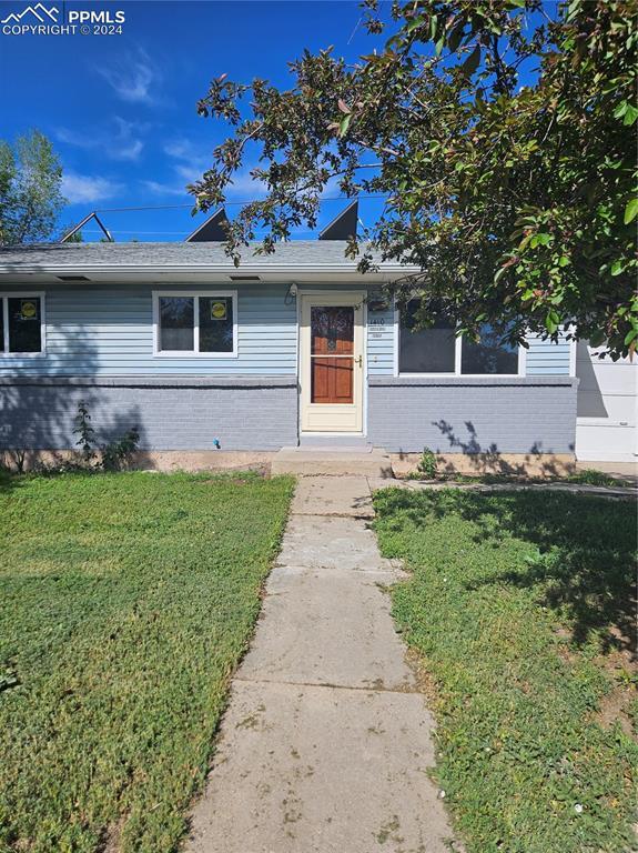 view of front facade with brick siding and a front yard