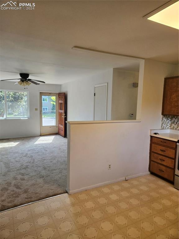 empty room with baseboards, light carpet, a ceiling fan, and light floors