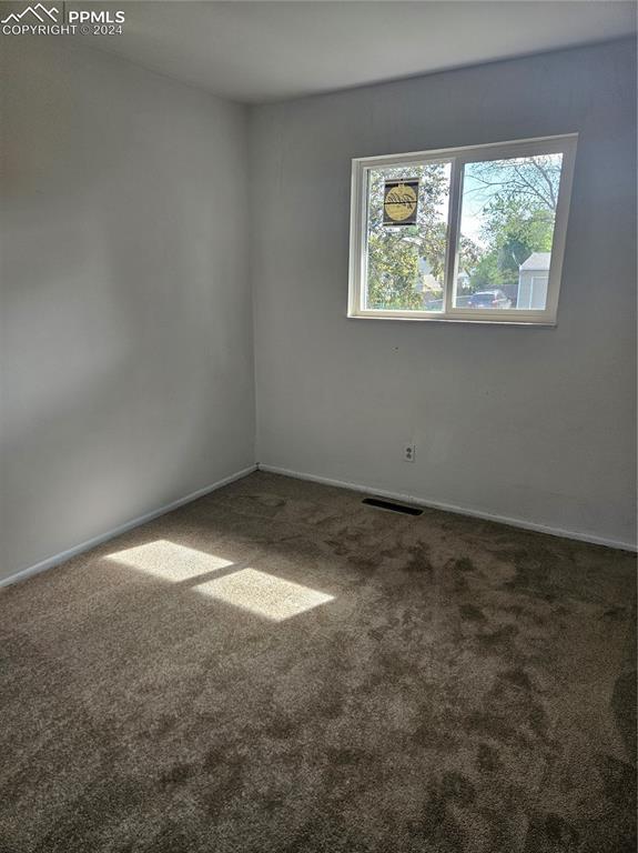 carpeted empty room featuring baseboards and visible vents