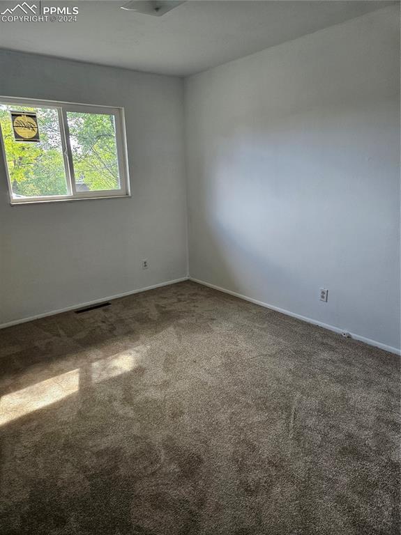 carpeted spare room with baseboards and visible vents