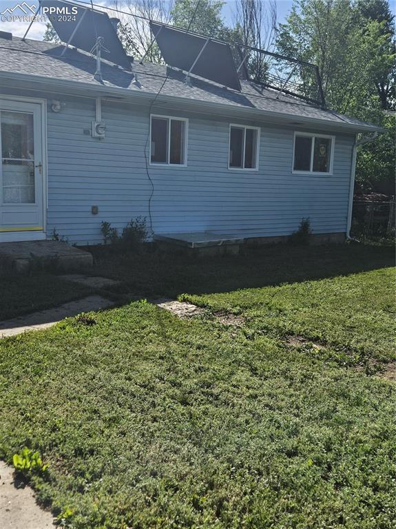 view of property exterior featuring roof with shingles and a yard