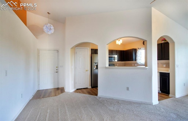 interior space with carpet floors, high vaulted ceiling, and baseboards