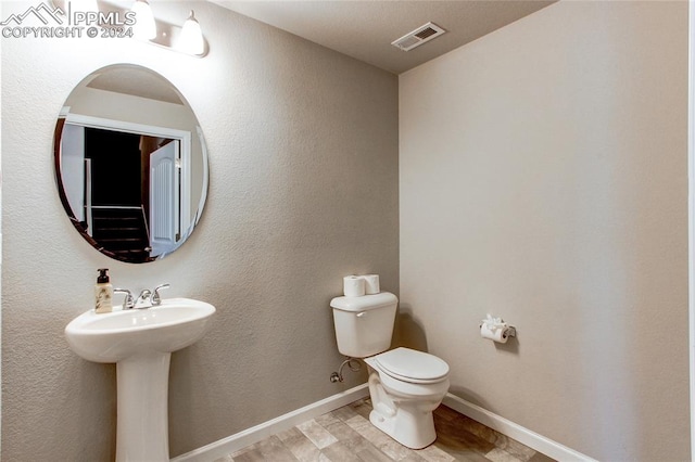 bathroom featuring toilet and wood-type flooring