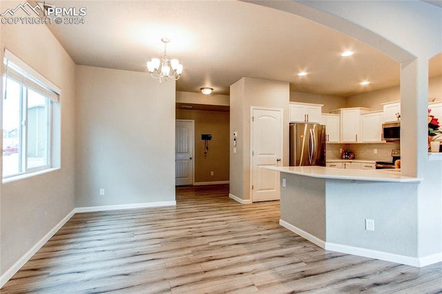 kitchen featuring white cabinets, backsplash, appliances with stainless steel finishes, and light hardwood / wood-style floors