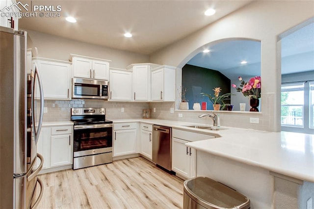 kitchen featuring light wood-type flooring, white cabinetry, appliances with stainless steel finishes, and decorative backsplash