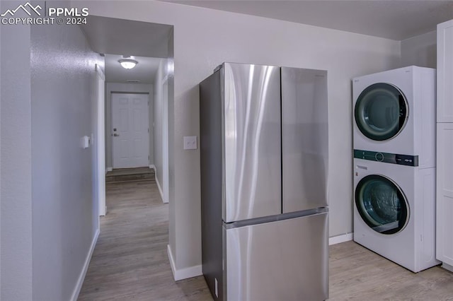 laundry area featuring stacked washer / drying machine and light hardwood / wood-style floors