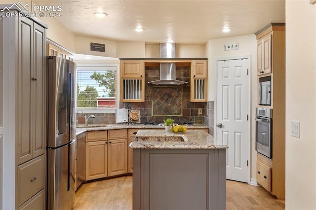 kitchen with stainless steel appliances, light brown cabinetry, a center island, and light wood-type flooring