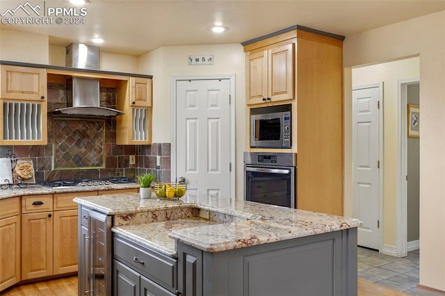 kitchen featuring appliances with stainless steel finishes, a center island, tasteful backsplash, and light brown cabinets