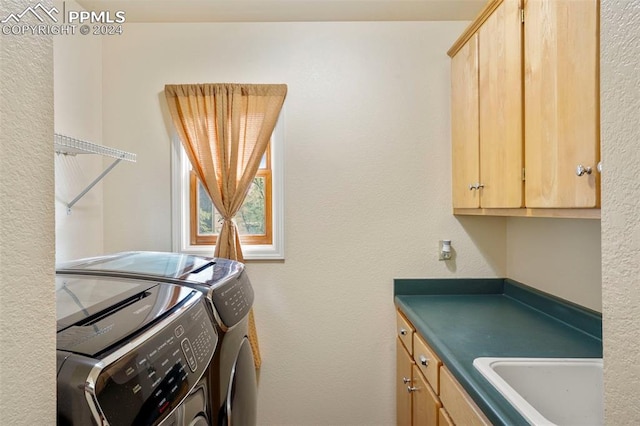 clothes washing area featuring washer and dryer, sink, and cabinets