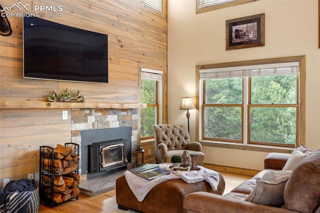 living room with a fireplace, light wood-type flooring, wood walls, and a wood stove