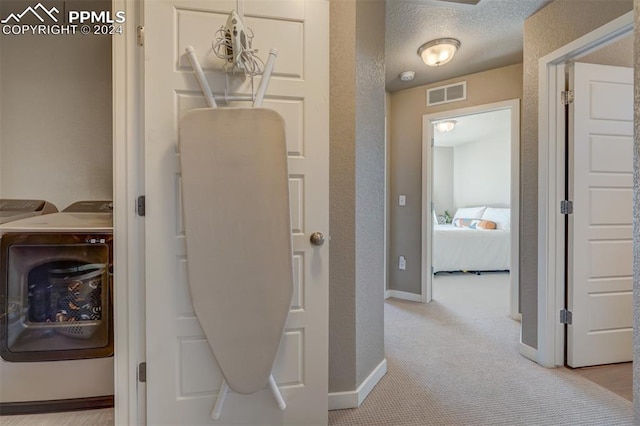 hallway with a textured ceiling and light carpet