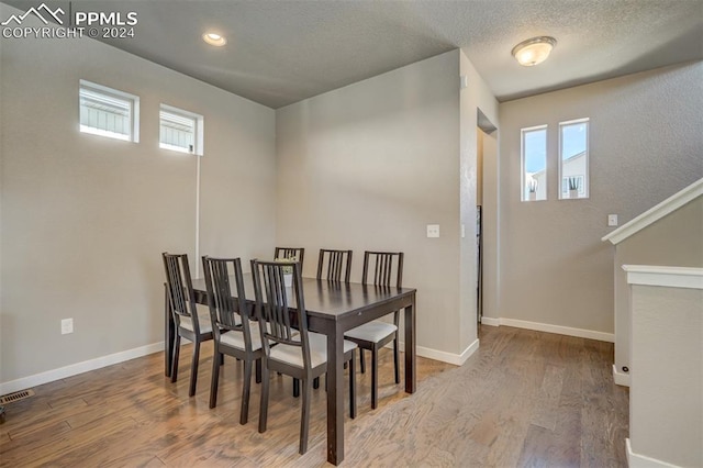 dining room featuring wood-type flooring and a textured ceiling