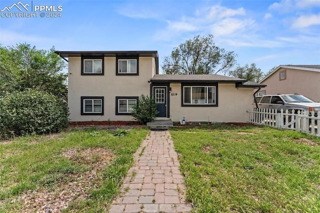 split level home featuring a front yard, fence, and stucco siding