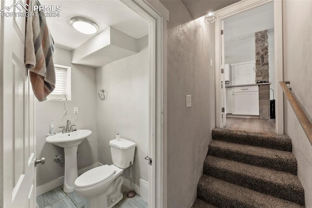 half bath with baseboards, a sink, and toilet