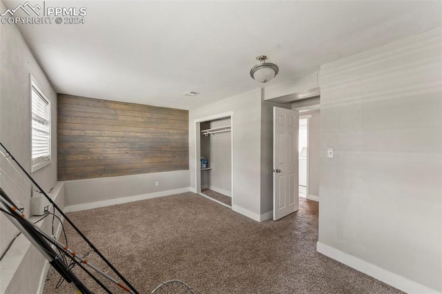 empty room with carpet floors, wood walls, and baseboards