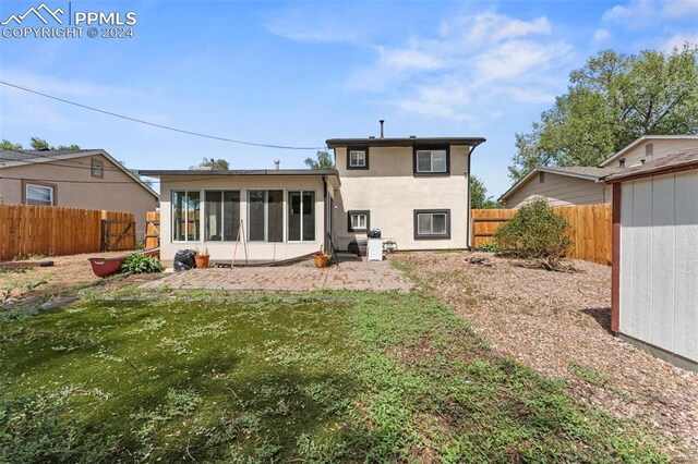 back of property with a yard, a storage unit, and a sunroom