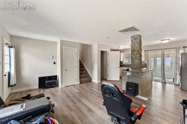 office area featuring light wood-type flooring, visible vents, decorative columns, and baseboards