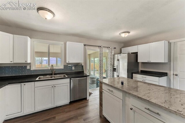 kitchen with dark hardwood / wood-style flooring, tasteful backsplash, stainless steel appliances, sink, and white cabinetry