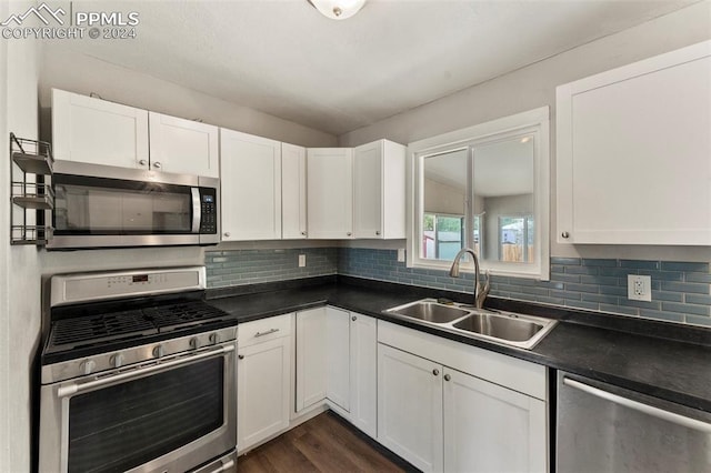 kitchen featuring dark countertops, appliances with stainless steel finishes, backsplash, and a sink