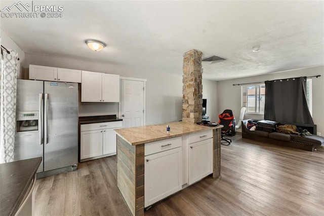 kitchen with visible vents, open floor plan, white cabinets, light wood-type flooring, and stainless steel fridge with ice dispenser