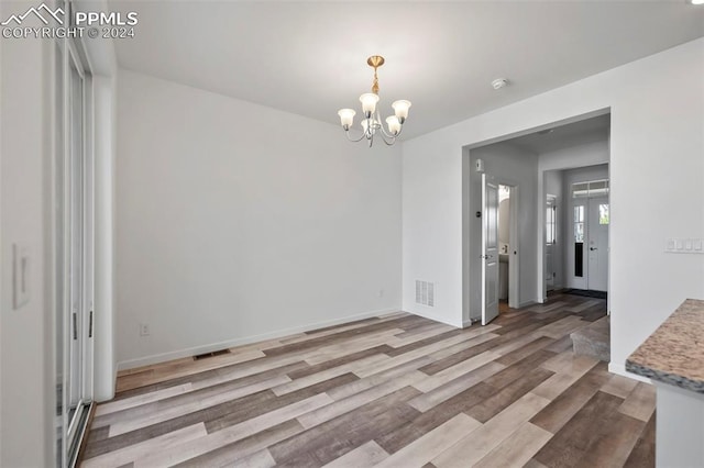 unfurnished dining area featuring light hardwood / wood-style floors and an inviting chandelier