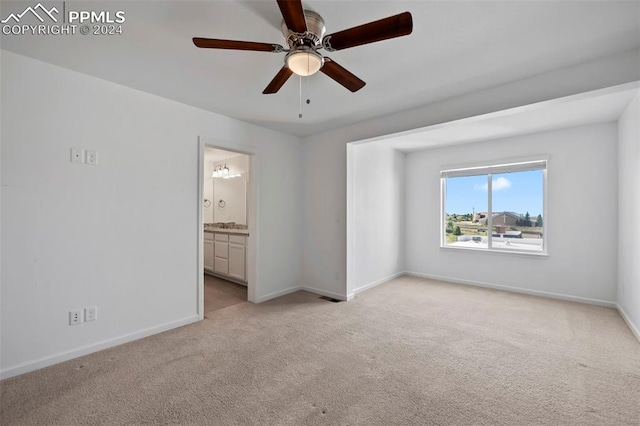 unfurnished bedroom with ceiling fan, ensuite bathroom, and light carpet