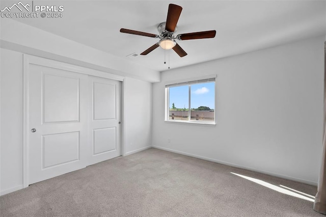 unfurnished bedroom featuring ceiling fan, light carpet, and a closet