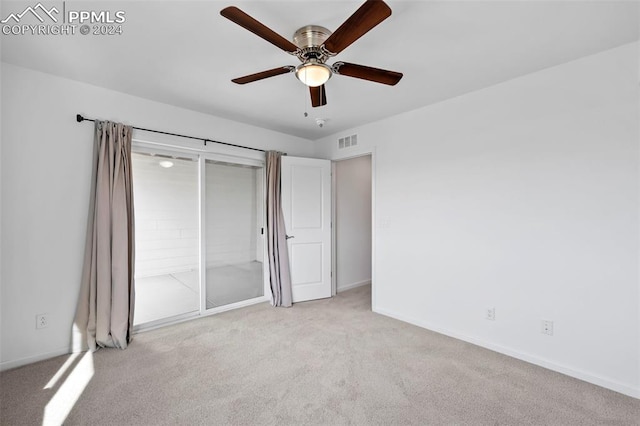 unfurnished bedroom with ceiling fan, light colored carpet, and a closet