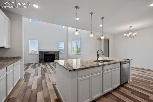 kitchen with white cabinetry, dishwasher, sink, hanging light fixtures, and a kitchen island with sink