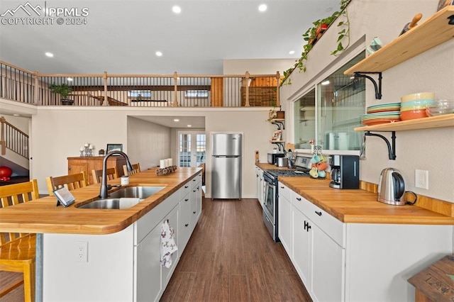 kitchen with wooden counters, dark wood-type flooring, white cabinetry, sink, and stainless steel appliances