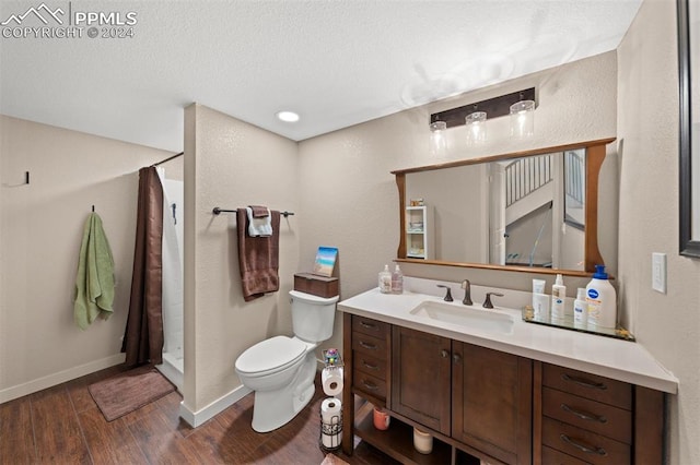 bathroom with hardwood / wood-style floors, a textured ceiling, vanity, curtained shower, and toilet