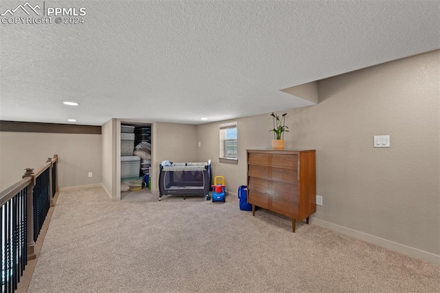 recreation room featuring a textured ceiling and light carpet