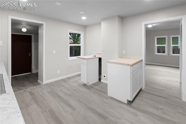 kitchen with white cabinets, wood counters, light hardwood / wood-style floors, and a center island