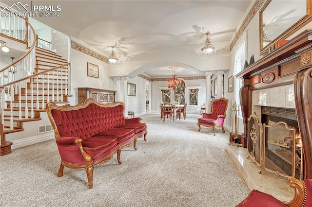 living room featuring a high end fireplace, crown molding, an inviting chandelier, and carpet