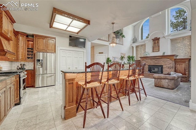 kitchen with dark stone countertops, a brick fireplace, stainless steel appliances, a kitchen breakfast bar, and decorative backsplash