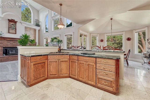 kitchen featuring a fireplace, dark stone counters, decorative light fixtures, and a high ceiling